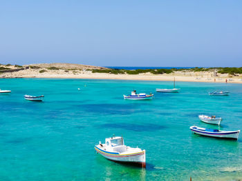 Sailboats moored on sea against clear sky