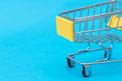 Close-up of shopping cart against blue background