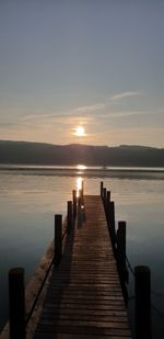 Wooden pier over lake against sky during sunset