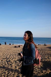 Woman standing on beach against sea against sky