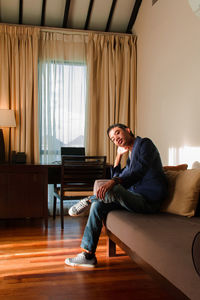 Portrait of young man sitting on sofa at home