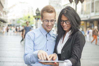 Portrait of smiling young man using smart phone in city