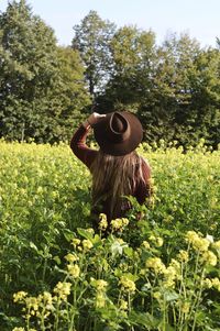 Rear view of woman wearing hat standing amidst plants