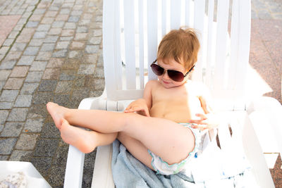 Small child in panama hat plays in the summer on sunny day near swimming pool