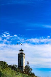 Low angle view of lighthouse by building against sky