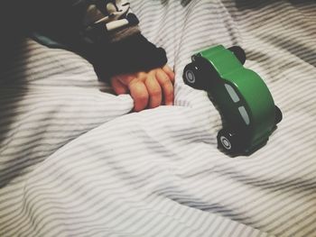 Close-up of hand holding toy on bed