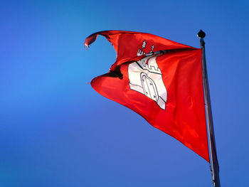 Low angle view of flag against clear blue sky