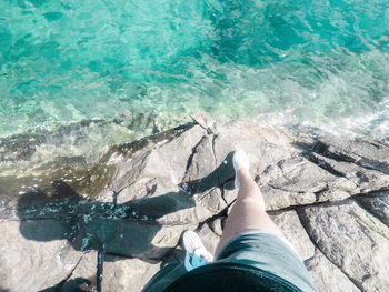 Low section of person relaxing by swimming pool