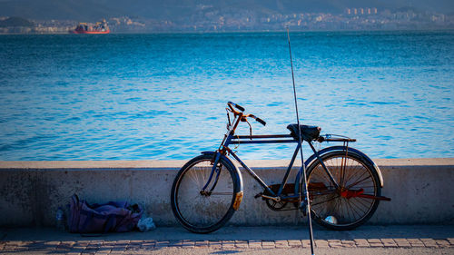 Bicycle by sea against blue sky