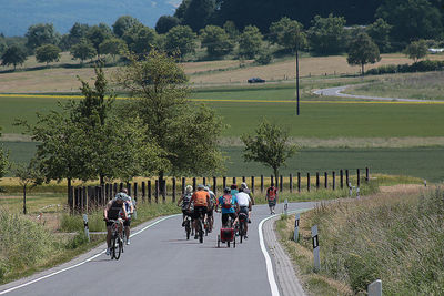 People riding bicycle on road against trees