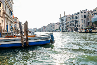 Boats in canal amidst buildings in city against clear sky