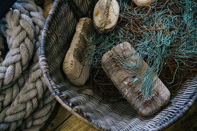 High angle view of fishing net and rock in wicker basket