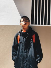 Portrait of young man standing against wall