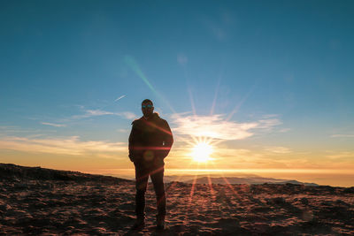 Man standing on land against sky during sunset