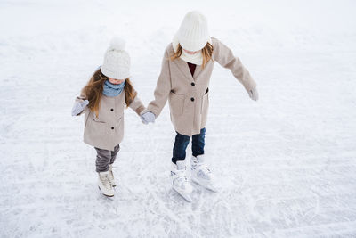 Rear view of women standing on snow covered landscape during winter