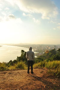 Rear view of young man looking at sea against sky