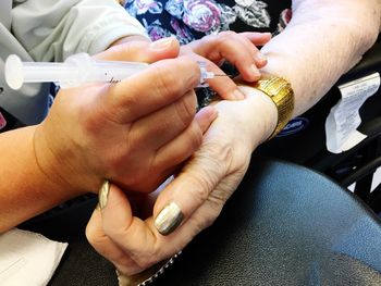 Cropped image of doctor injecting senior female patient