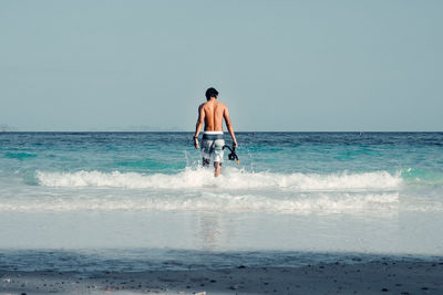Rear view of man at beach against clear sky