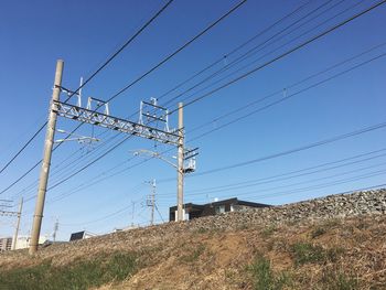 Low angle view of electricity pylon on field against clear sky