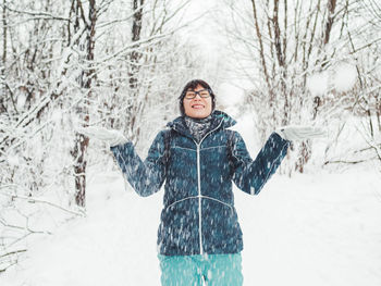 Smiling woman is playing with snow. fun in snowy winter forest. woman laughs. sincere emotions.