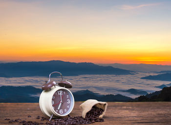 High angle view of clock on sea against mountain during sunset