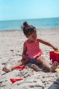 Rear view of girl sitting on sand at beach