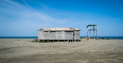 Lifeguard hut on beach against blue sky