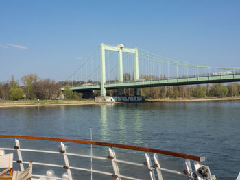 Suspension bridge over river against clear sky