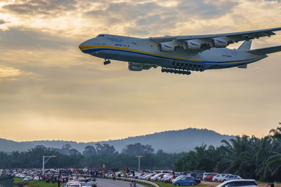 Airplane on runway against sky during sunset