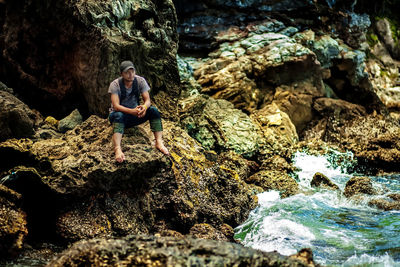 Man standing on rock by sea