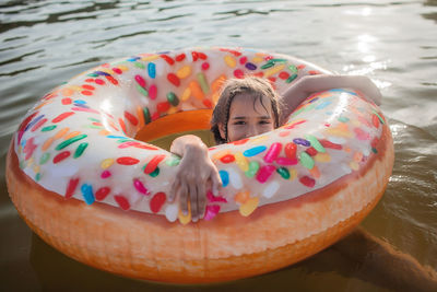 Girl swims with big donut inflatable ring on lake on hot summer day, happy summertime, cottagecore