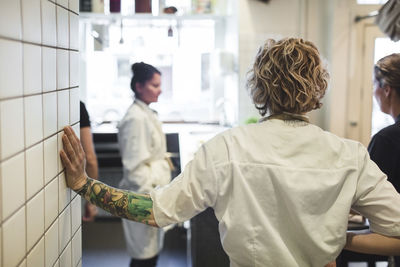 Rear view of chef standing with female colleagues in restaurant kitchen