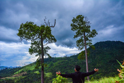 Man by tree against sky