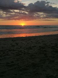 Scenic view of sea against dramatic sky during sunset