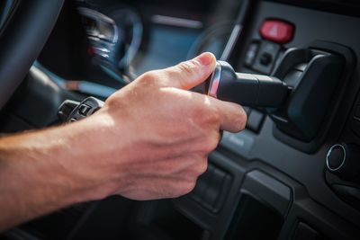 Cropped hand holding equipment in car