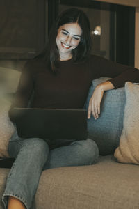 Portrait of young woman sitting on sofa at home