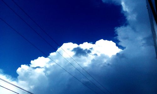 Low angle view of electricity pylon against blue sky