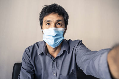 Portrait of man wearing mask sitting against wall