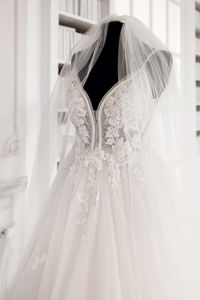 A white wedding dress and a veil, put on a black mannequin without a head