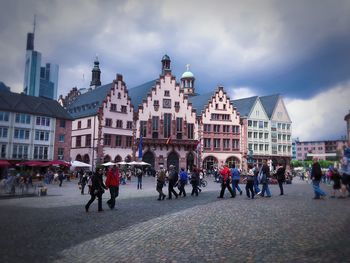 People at town square against cloudy sky
