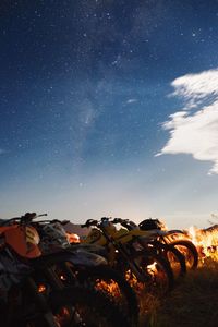 Motorbikes parked on field against sky at night