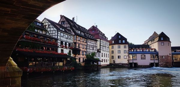 Buildings by river against sky