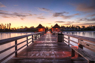 Pier over lake against sky during sunset