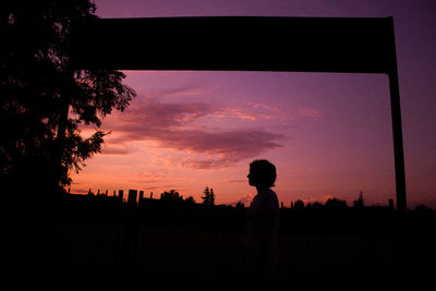 Silhouette man standing on field against sky at sunset