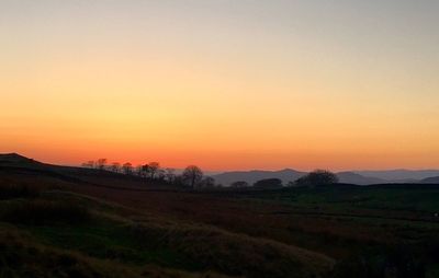 Scenic view of field against orange sky