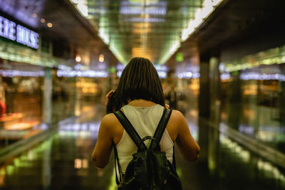 Rear view of young woman walking in illuminated building