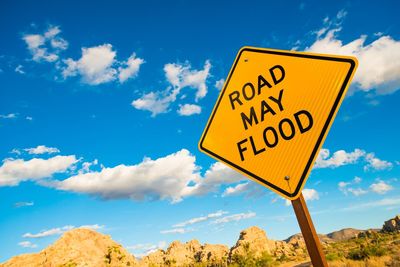 Low angle view of road sign against blue sky