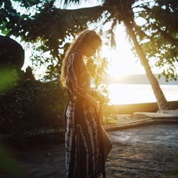 View of woman on beach by palm tree