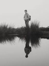 Reflection of young woman standing in lake against clear sky