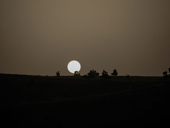 Silhouette people on field against sky at night